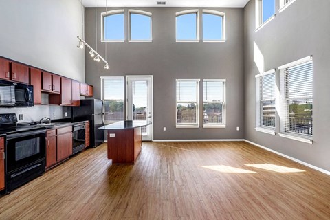 a kitchen and living room with windows and a wood floor